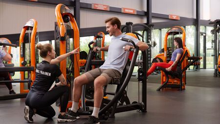 Personal Trainer Giving support on the use of a chest press machine